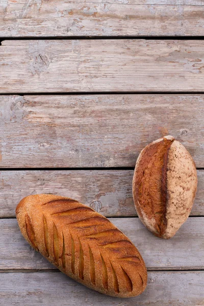 Bovenaanzicht van ambachtelijk brood op houten ondergrond. — Stockfoto