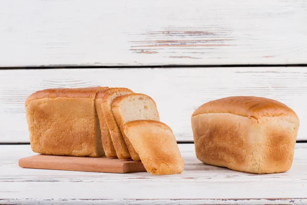 Skivad och hela bröd på trä bakgrund. — Stockfoto