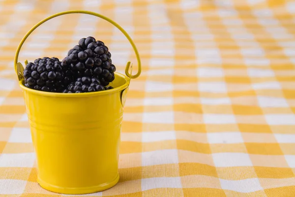 Tiny yellow bucket with blackberries. — Stock Photo, Image