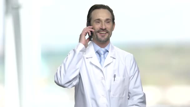 Веселый мужчина в белом халате разговаривает по телефону . — стоковое видео