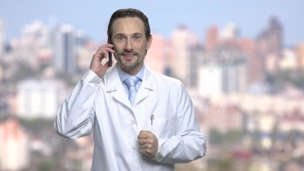 Joyful man in white coat talking on phone. — Stock Video