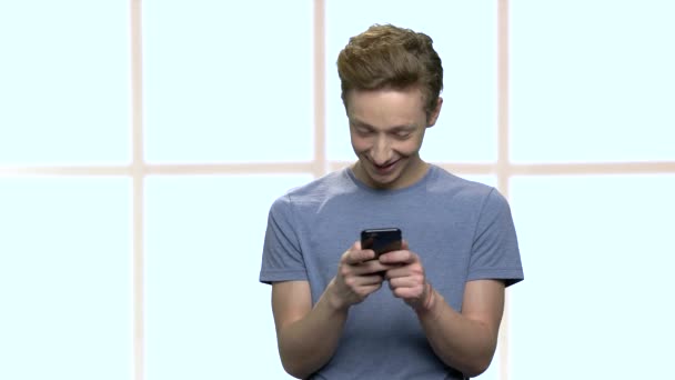 Glimlachende tiener jongen met behulp van smartphone. — Stockvideo