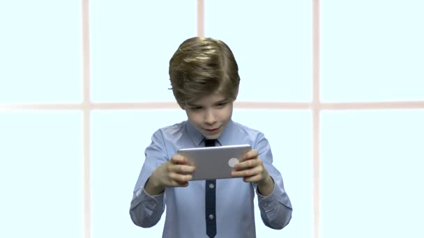 Liten kaukasisk pojke spelar spel på smartphone. — Stockvideo