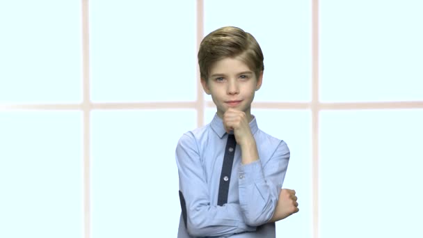 Sebevědomý malý chlapec na kostkovaném pozadí okna. — Stock video