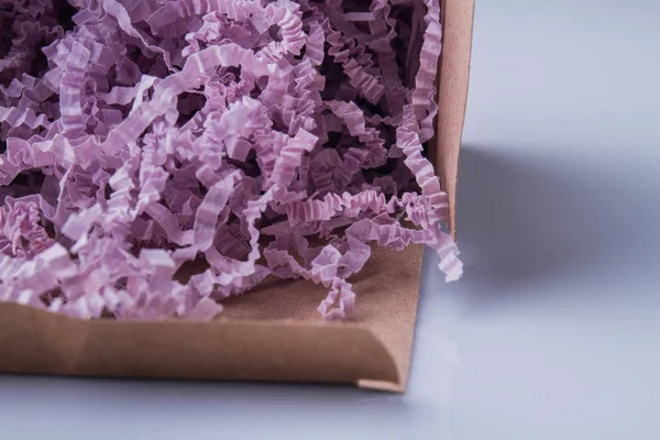 Close-up purple shredded paper in a cardboard box.