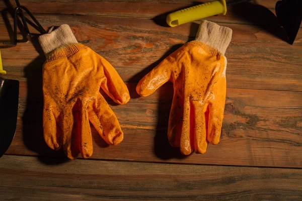 Used dirty garden gloves over wooden table background. — ストック写真