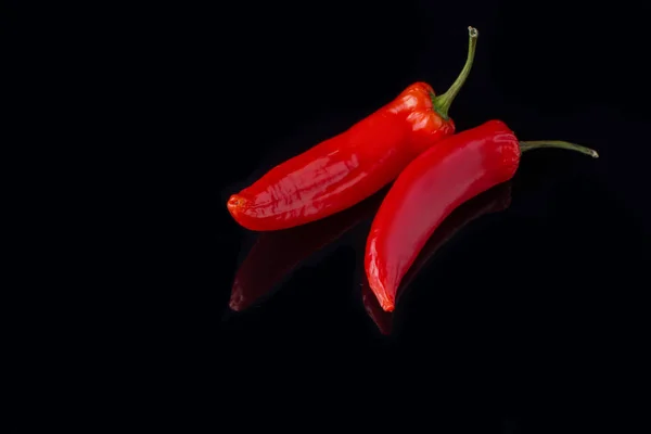 Świeże czerwone papryki chili na czarnym tle. — Zdjęcie stockowe