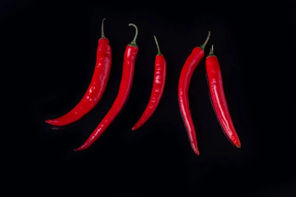 Fila de pimentas vermelhas quentes no fundo preto . — Fotografia de Stock