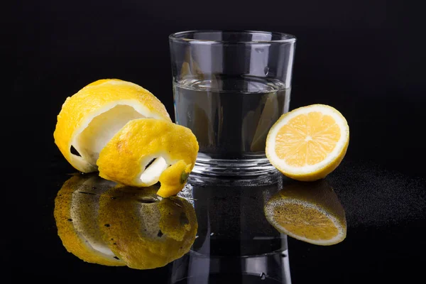 Un vaso de agua con la mitad de limón . — Foto de Stock