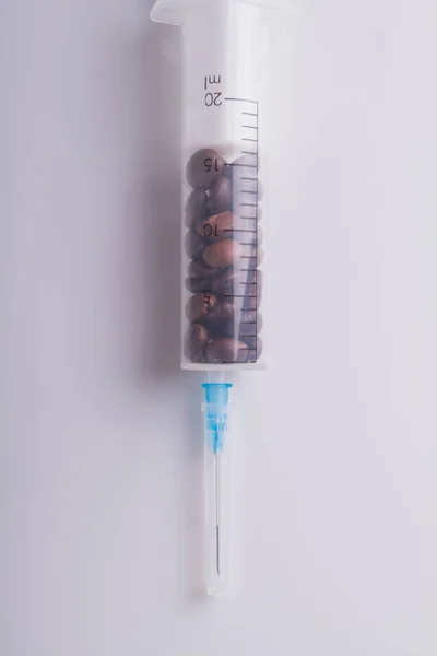 Medizinische Spritze voller Kaffeebohnen vor weißem Hintergrund. — Stockfoto