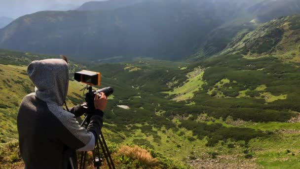 Caméraman en coulisses filmant des montagnes pendant une journée . — Video