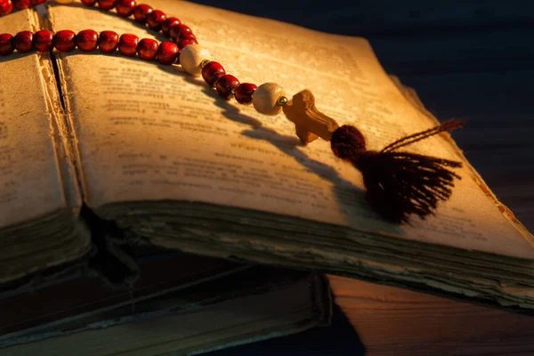Rosary with red beads and old ancient bible book. — Stock Photo, Image