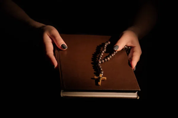 Manos femeninas sosteniendo la sagrada Biblia y collar de rosario . — Foto de Stock