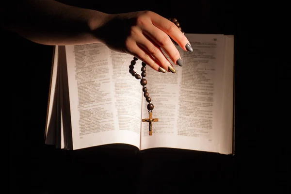 Mãos segurando a Bíblia e orando com um rosário . — Fotografia de Stock