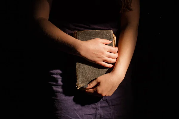 Yound woman holding old vintage book with both hands.