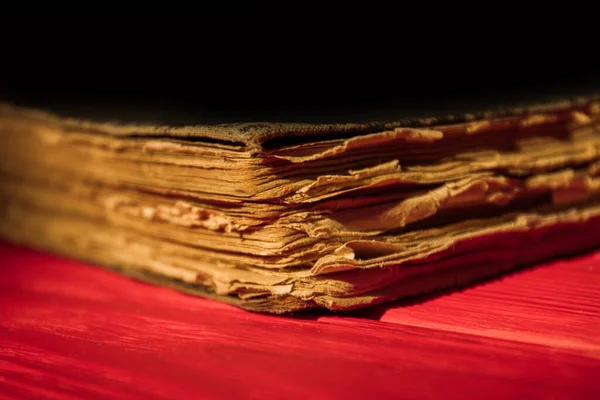 Very old ancient closed book on red wood surface.