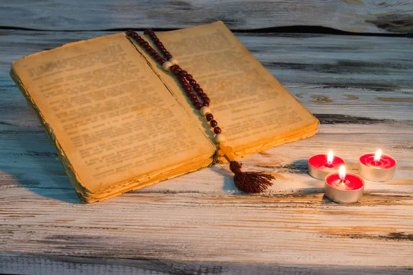 Biblia aberta com velas rosário . — Fotografia de Stock