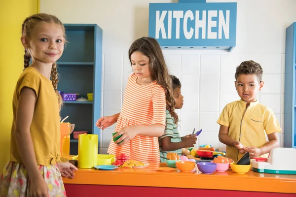 Happy kids zabawy z zabawką kuchnia w pokoju dla dzieci. — Zdjęcie stockowe
