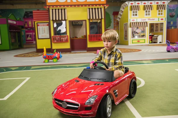 Chłopiec prowadzi mini samochód w parku rozrywki. — Zdjęcie stockowe