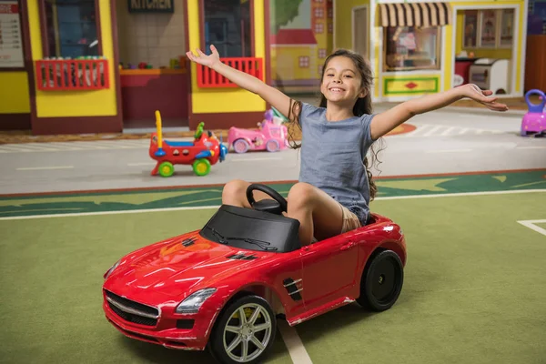 Happy little girl in toy car at game center. — ストック写真