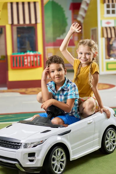 幸せな子供たちはおもちゃの車に座ってカメラを見て. — ストック写真