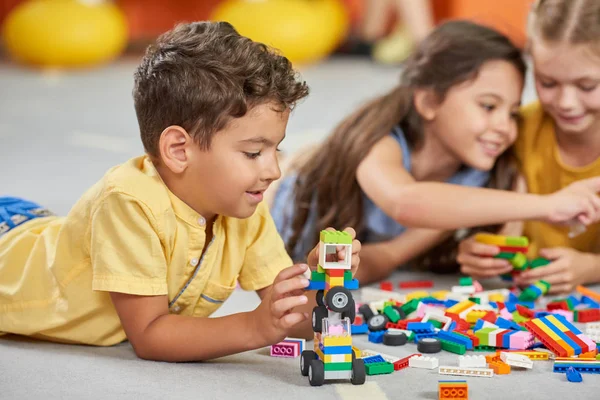 Enfants jouant à des jouets en bloc dans la salle de jeux à la crèche . — Photo