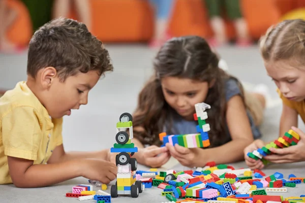 Meninos e meninas brincando com brinquedos de bloco na sala de jogos . — Fotografia de Stock