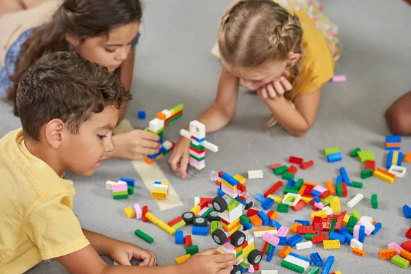 Enfants jouant à des jouets en bloc dans la salle de jeux à la crèche . — Photo