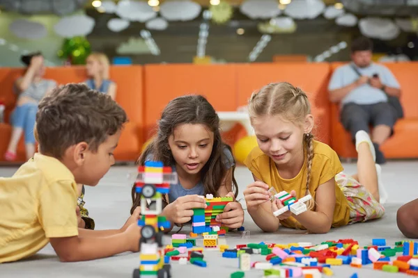 Ragazzini e ragazze che giocano con giocattoli a blocchi in sala giochi . — Foto Stock