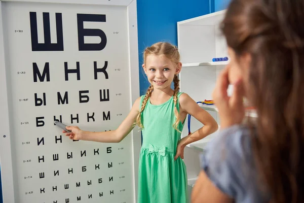 Children playing doctor and patient in ophthalmologist office.