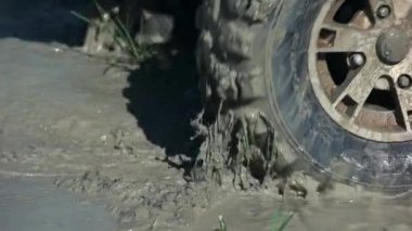 Extreme close up offroad wheel spinning in a dirty water.
