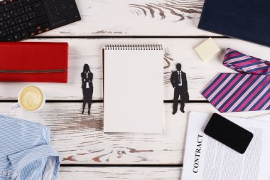 Man and woman paper figures near notebook.