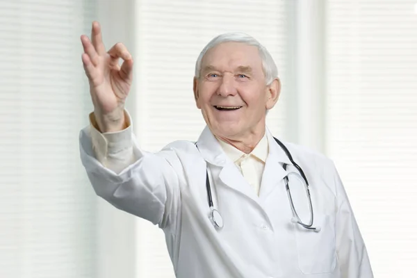 Sorrindo médico caucasiano sênior com sinal ok . — Fotografia de Stock