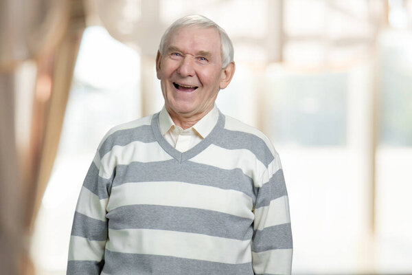 Счастливый старый дед в помещении смеется
.