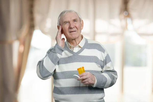 Old male senior with headache taking pills. — Stockfoto