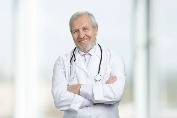 Sorrindo velho médico com braços cruzados de pé . — Fotografia de Stock