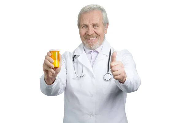 Médico sênior com lata de laranja de comprimidos e polegar para cima . — Fotografia de Stock