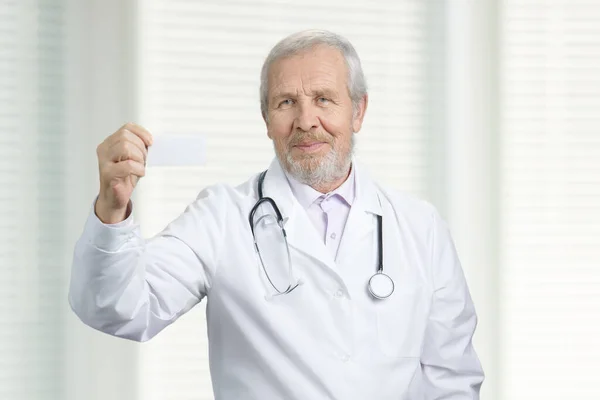 Portrait of old doctor with business card. — Stockfoto