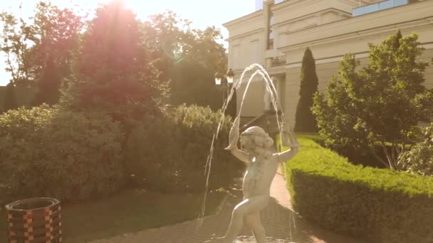 Splashing fountain sculpture of boy with fishes in his hands. — Stock Video