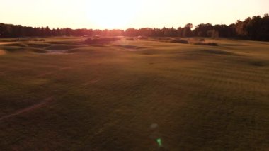 Gün batımı parlıyor ve engebeli çimen tarlası.