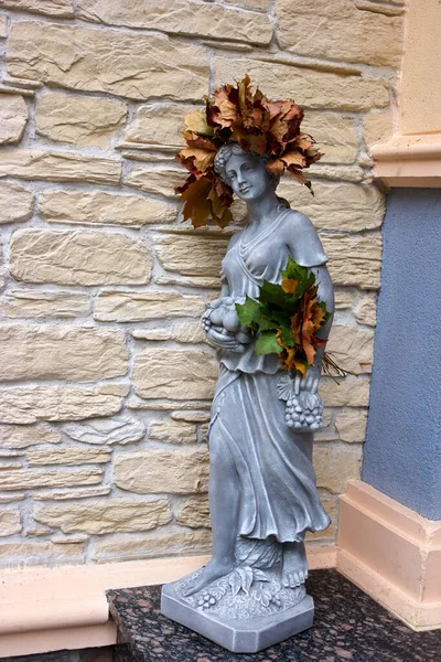 Young woman sculpture with autumnal leaves.