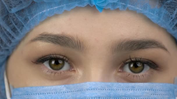 Close up blinking brown eyes of a female doctor with mask. — ストック動画