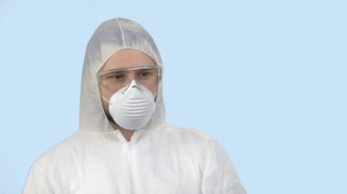 Antiviral koruyucu giysili, maskeli ve gözlüklü genç bir adam..