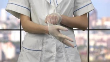 Kadın doktor lastik tıbbi eldiven giyer..