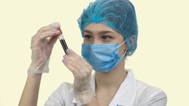 혈액 검사 튜브로 보호 마스크를 쓰고 있는 젊은 여자 의사. — 비디오