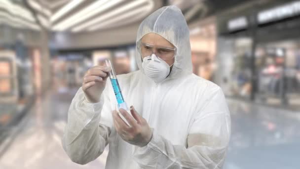 Hombre con traje protector antiviral sosteniendo tubo de ensayo con medicina azul . — Vídeos de Stock