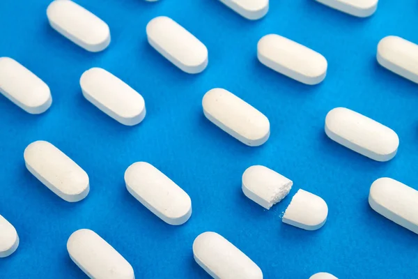Fila de pílulas brancas no fundo azul . — Fotografia de Stock