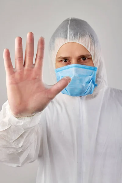 Un científico médico usa ropa protectora y muestra una señal de stop . —  Fotos de Stock