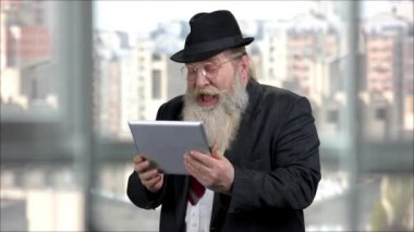 Tabletli yaşlı bir adamın tabletli portresi yüksek sesle gülüyor..