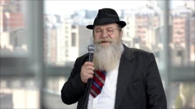 Saygıdeğer kıdemli adam mikrofonla konuşma yapıyor..